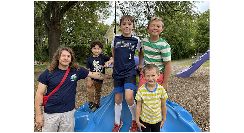 four smiling kids and their counselor at the playground